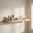 Styled floating oak shelf with ceramic vases, books, and a small glowing lamp